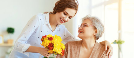 a caregivere giving flowers to the senior woman