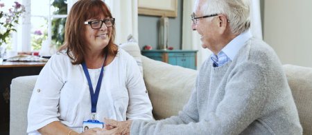 a caregiver and a senior man talking