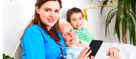 a caregiver and a senior woman looking at a mobile tablet