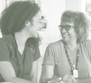 a caregiver and a senior woman smiling at each other