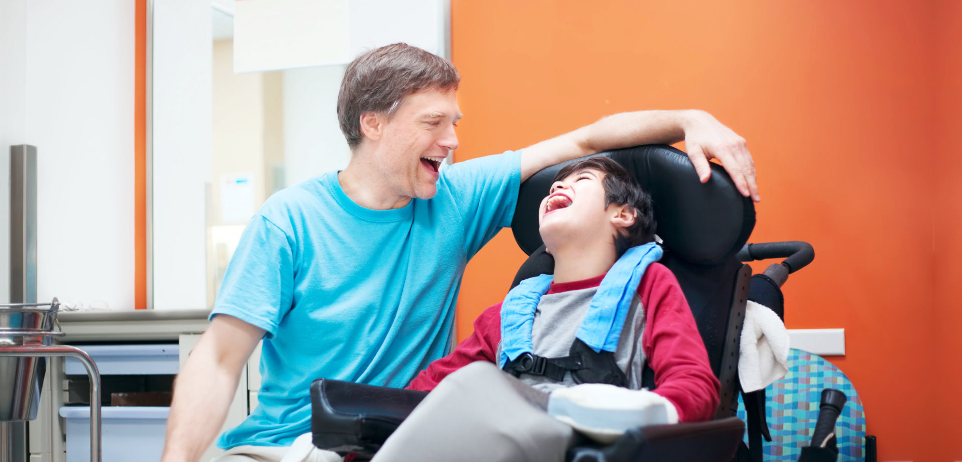 a caregiver and a child with disability laughing